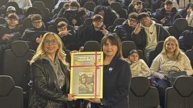 due donne in posa che si fanno fotografare e dietro una platea di persone